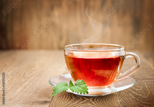 transparent glass cup of hot tea and Melissa leaves on wooden background