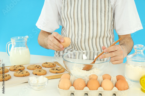 Concept of cooking cookies with young man against blue background