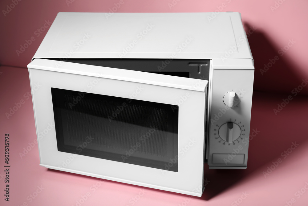 Fototapeta premium New modern microwave oven on pink background