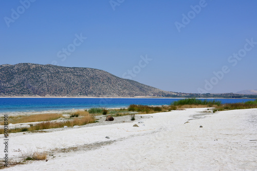 turkish lake Salda in sunny day with white sand and mountain on background