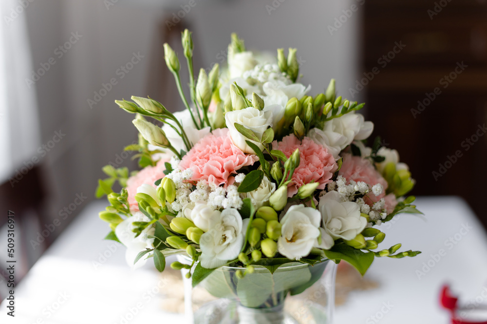 Soft bridal bouquet of fresh flowers in glass vase on celebratory table closeup, blurred background. Elegant attribute and tradition. Beautiful and romantic wedding, luxurious celebration