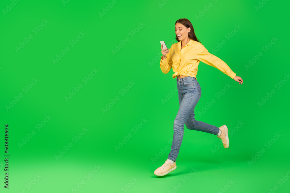 Excited Woman Using Smartphone Running And Communicating Over Green Background Excited Woman Using Smartphone Running And Communicating Over Green Background