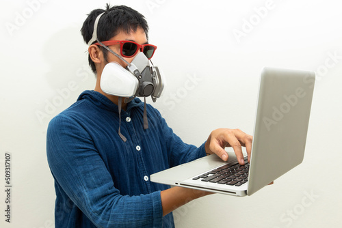 Man protection cartridge respirator gas mask  using laptop.