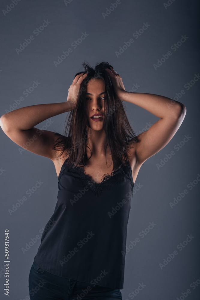 Portrait of a beautiful female model looking serious at the camera while touching her brunette hair Portrait of a beautiful female model looking serious at the camera while touching her brunette hair