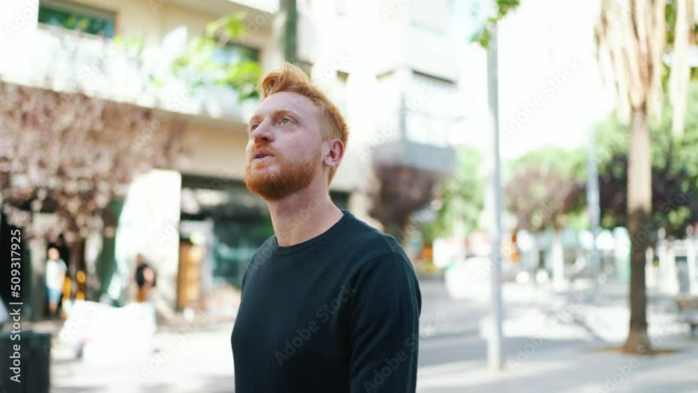 Cheerful red haired man walking and looking around on the street Cheerful red haired man walking and looking around on the street