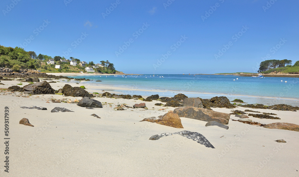 view of a beach with fine white sand and rocks in front of  blue water in Brittany - France