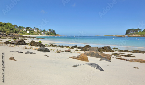 view of a beach with fine white sand and rocks in front of  blue water in Bri...
