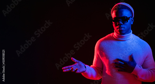 Pointing man. Neon light banner. Offer advertising. Serious confident handsome guy in vivid red blue glow presenting content on dark copy space background.