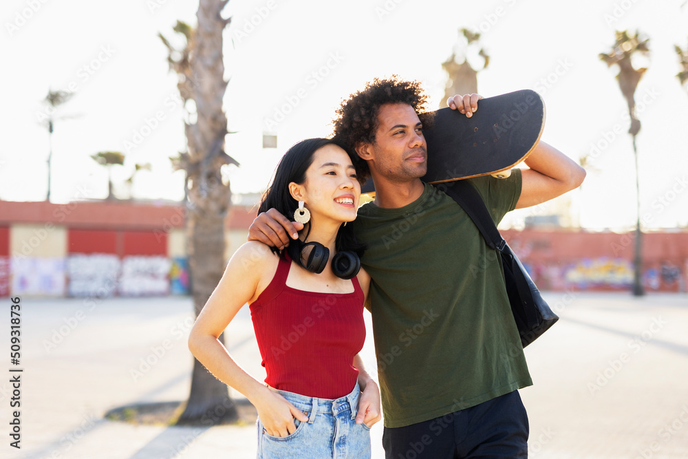 Beautiful couple having fun outdoors. Portrait of an excited young couple with skateboard.
