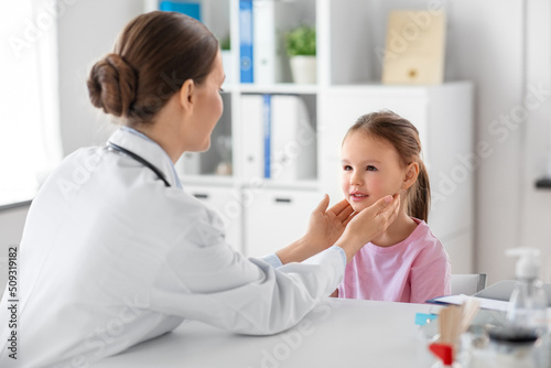 medicine  healthcare and pediatry concept - female doctor or pediatrician checking little girl patient s tonsils on medical exam at clinic