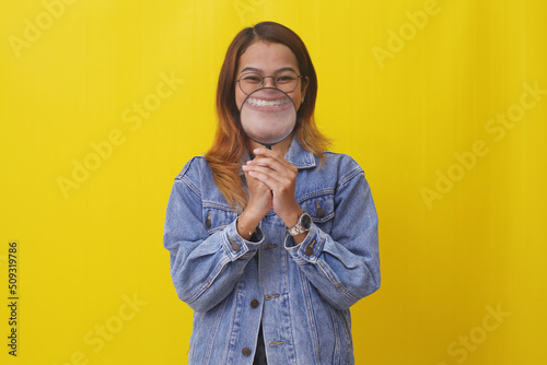 Funny young asian woman standing while holding magnifying glass in front her mouth