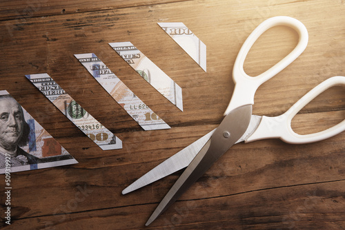 One hundred dollar bill is sliced into pieces with steel scissors.