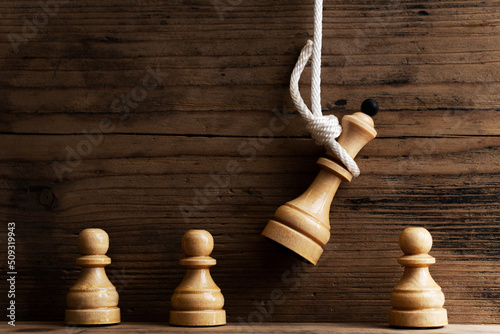 Billede på lærred Wooden chess queen hanging on a white rope with pawns standing below