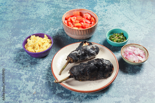 barbeque of brinjal ready to cook with chopped tomatoes, onions, chilies and fried egg 