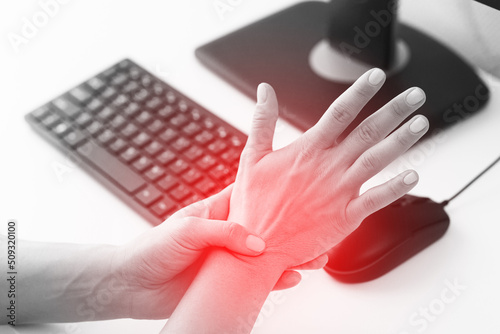 Woman working in office with a carpal tunnel syndrome or wrist joint inflammation