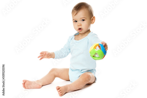 Little boy in romper sitting and playing with plastic toy.