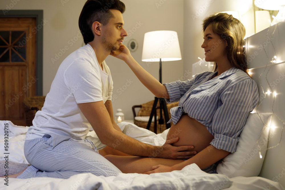 Obraz premium Young couple are waiting for a baby. Husband and his pregnant wife relax on the bed.