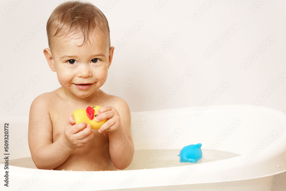 Little boy playing with rubber duck while taking a bath.