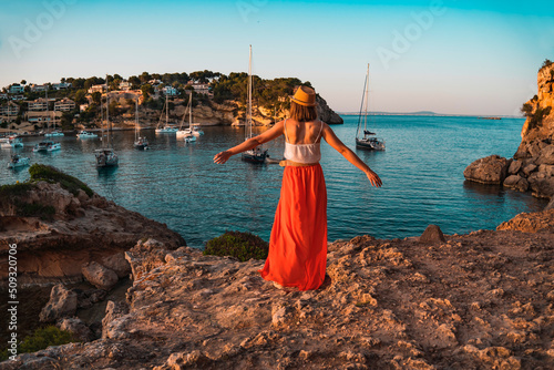 Young woman on holiday with her arms stretched out happily looking at the landscape, in the cove of Portal Vells, island of Palma de Mallorca, Spain. photo