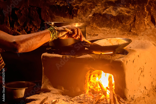 indian village woman cooking making roti bread in sitting kitchen 