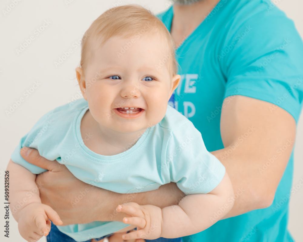 Portrait of athletic man with pumped up arms holding and raising smiling little baby closeup, white background. Whole family workout, father and child. Sport and healthy lifestyle concept Portrait of athletic man with pumped up arms holding and raising smiling little baby closeup, white background. Whole family workout, father and child. Sport and healthy lifestyle concept