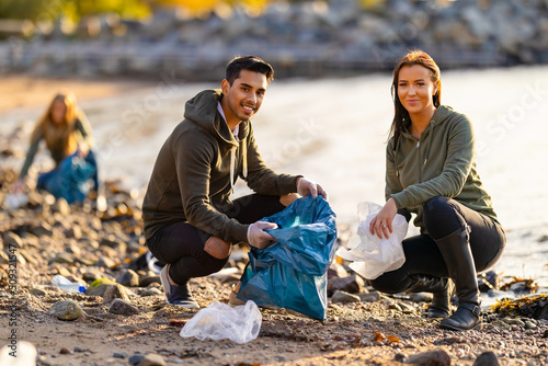 Fotografie Team of dedicated and smiling volunteers collecting plastic garbage at beach