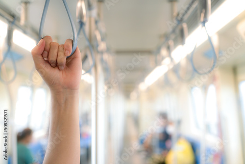 Hand holding a handle on the electric train for public transportation in Bangkok
