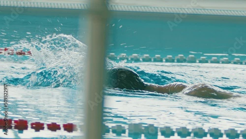 Muscular young man training and swims crawl stroke along the pool lane. Healthy lifestyle concept