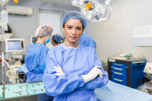 Portrait of confident female surgeon. Healthcare worker is against illuminated lights in hospital.