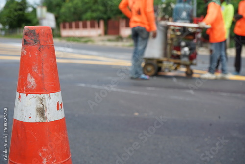 Blurred image. Workers are painting the edge of the road.