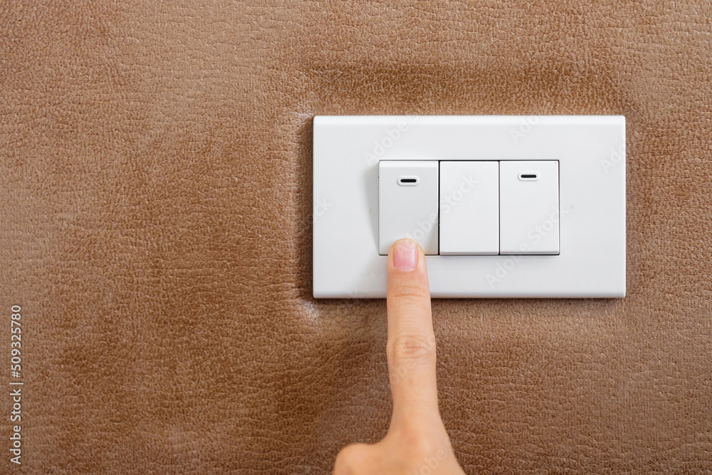 finger turn on or off on light switch on wall at home. Energy Saving, power, electrical and lifestyle concepts finger turn on or off on light switch on wall at home. Energy Saving, power, electrical and lifestyle concepts