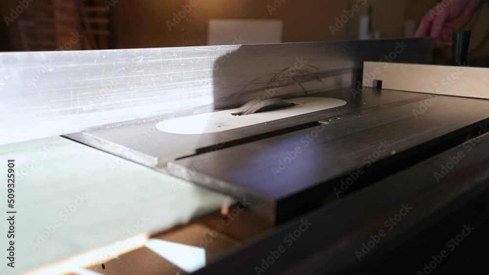 A craftsman starts up a table saw and cuts a groove in piece of wood using a dado set in slow motion. A craftsman starts up a table saw and cuts a groove in piece of wood using a dado set in slow motion.
