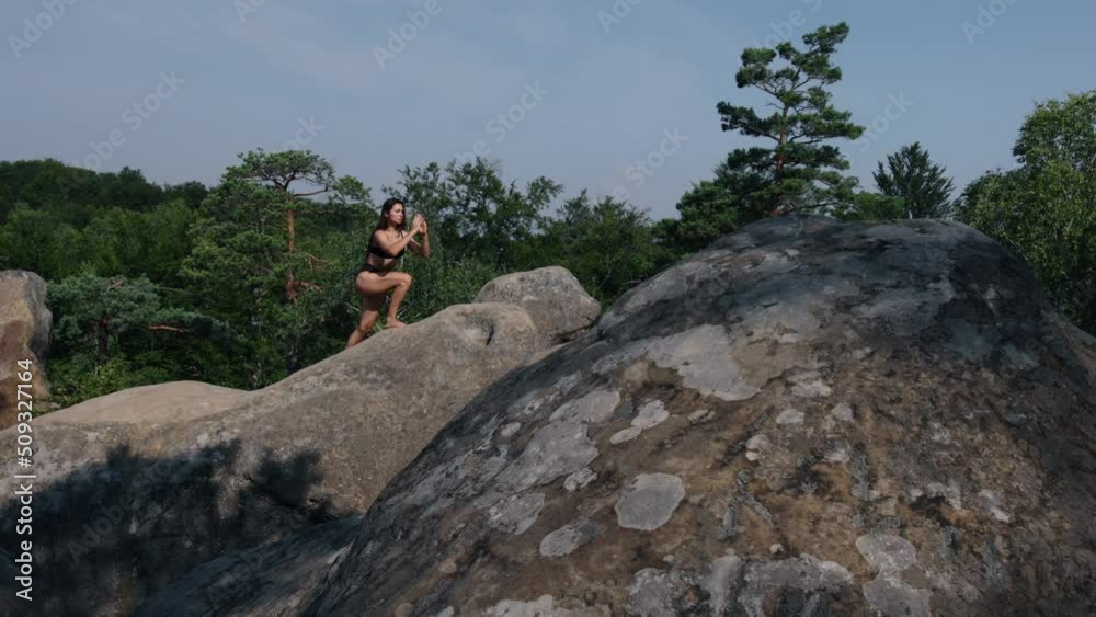 Pretty woman balancing on one leg climbs a cliff. Concept of sport, wellness and health. Young smiling lady doing active fitness workout, satisfied fit woman. Pretty woman balancing on one leg climbs a cliff. Concept of sport, wellness and health. Young smiling lady doing active fitness workout, satisfied fit woman.