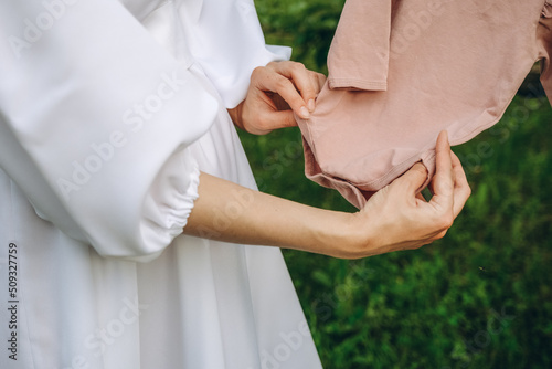 A pregnant woman, in anticipation of the birth of a baby, prepares clothes for him.