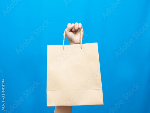 Hand showing paper bag blue background isolated