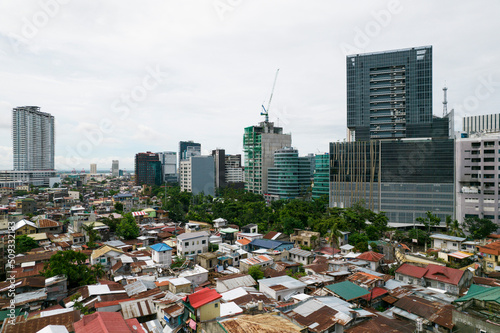 Cebu City, Philippines - Contrast of incomes, modern office buildings loom over crowded houses in a slum area. photo