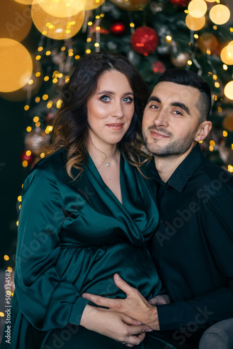 loving man and pregnant woman on background of Christmas decorations