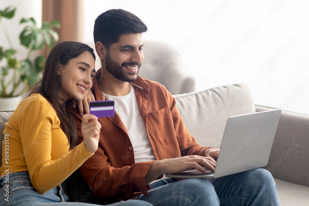 Happy Arabic Buyers Couple Shopping Online Via Laptop At Home Happy Arabic Buyers Couple Shopping Online Via Laptop At Home