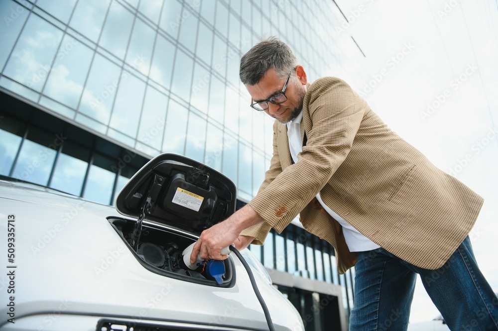 a businessman charges an electric car a businessman charges an electric car
