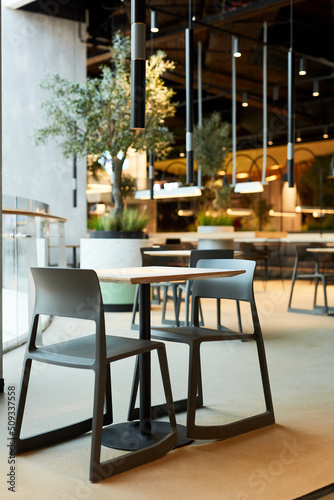 Vertical background image of table and chairs set in loft style food court interior