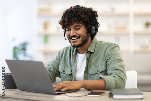 Positive handsome indian guy working online, having video conference