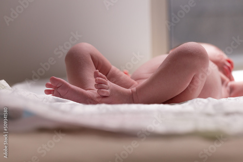 Sweet small feet of newborn baby on light blurred background.