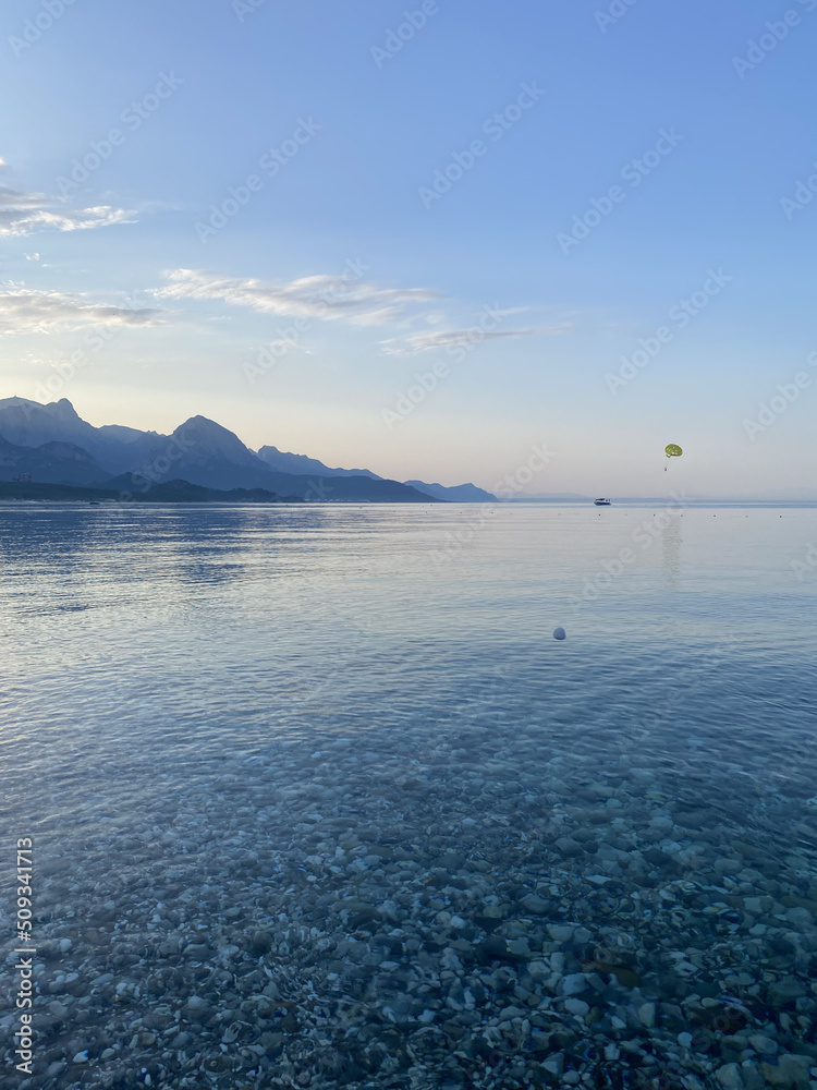 Obraz premium Pebbles on the seashore, sea background. A sea wave washes a pebble beach. View beach on the coast of Mediterranean sea in Kemer district of Antalya Province, Turkey