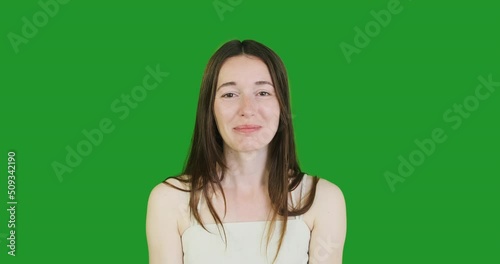 young woamn grimaces and shows her tongue. Green screen, chroma key, portrait, close-up. photo