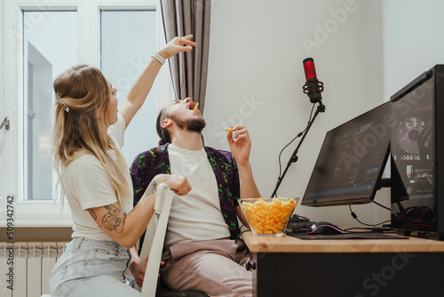 Couple eating cheese puffs while playing video games or watching something online at home