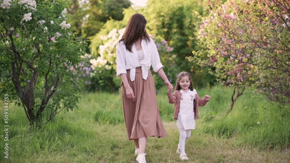 Mom and daughter are walking on the grass. The family spends leisure time in the park. Mom and daughter are walking on the grass. The family spends leisure time in the park.