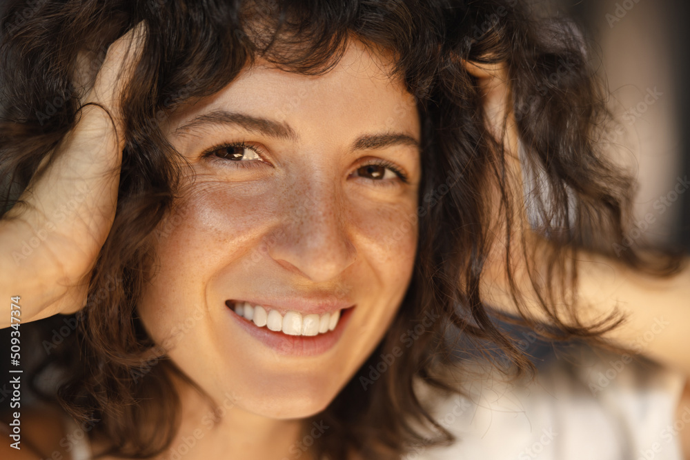 Close-up of beautiful young caucasian girl model posing smiling for camera. Brunette with short haircut is holding her head. Concept of enjoying moments Close-up of beautiful young caucasian girl model posing smiling for camera. Brunette with short haircut is holding her head. Concept of enjoying moments