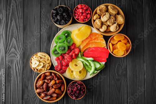 set of various dried fruits on a black wooden rustic background