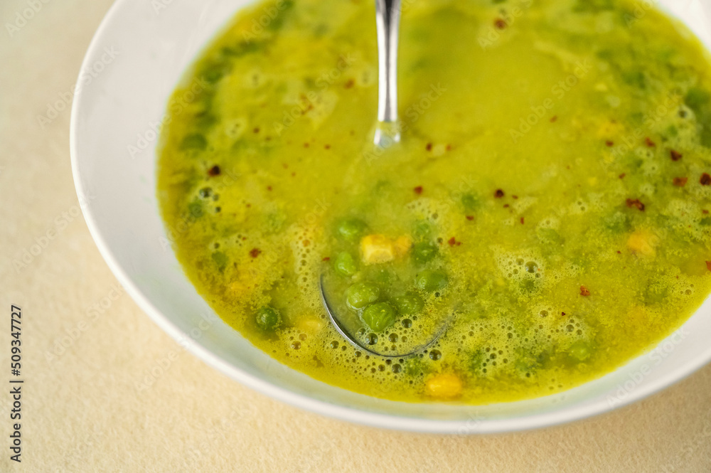 Pea and maize soup in white plate on yellow background. Pea and maize soup in white plate on yellow background.