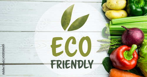 Image of eco friendly text in green, over fresh vegetables on white wooden boards